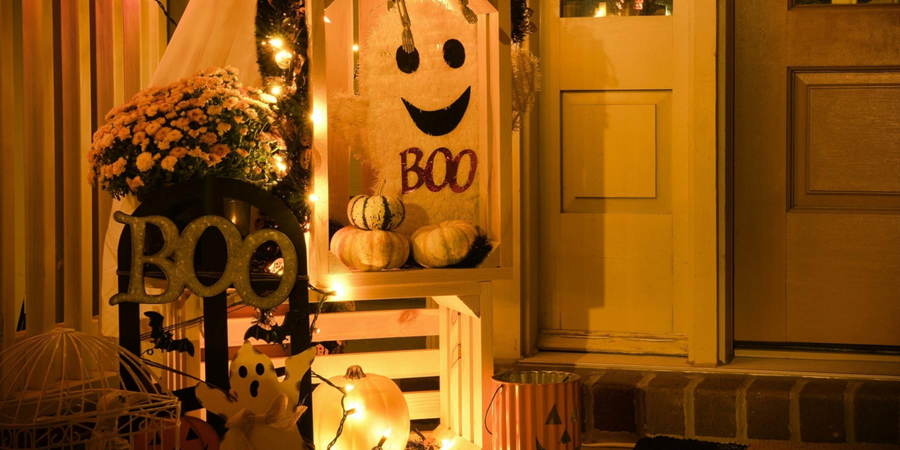 Small display of ghosts and white pumpkins with orange lights