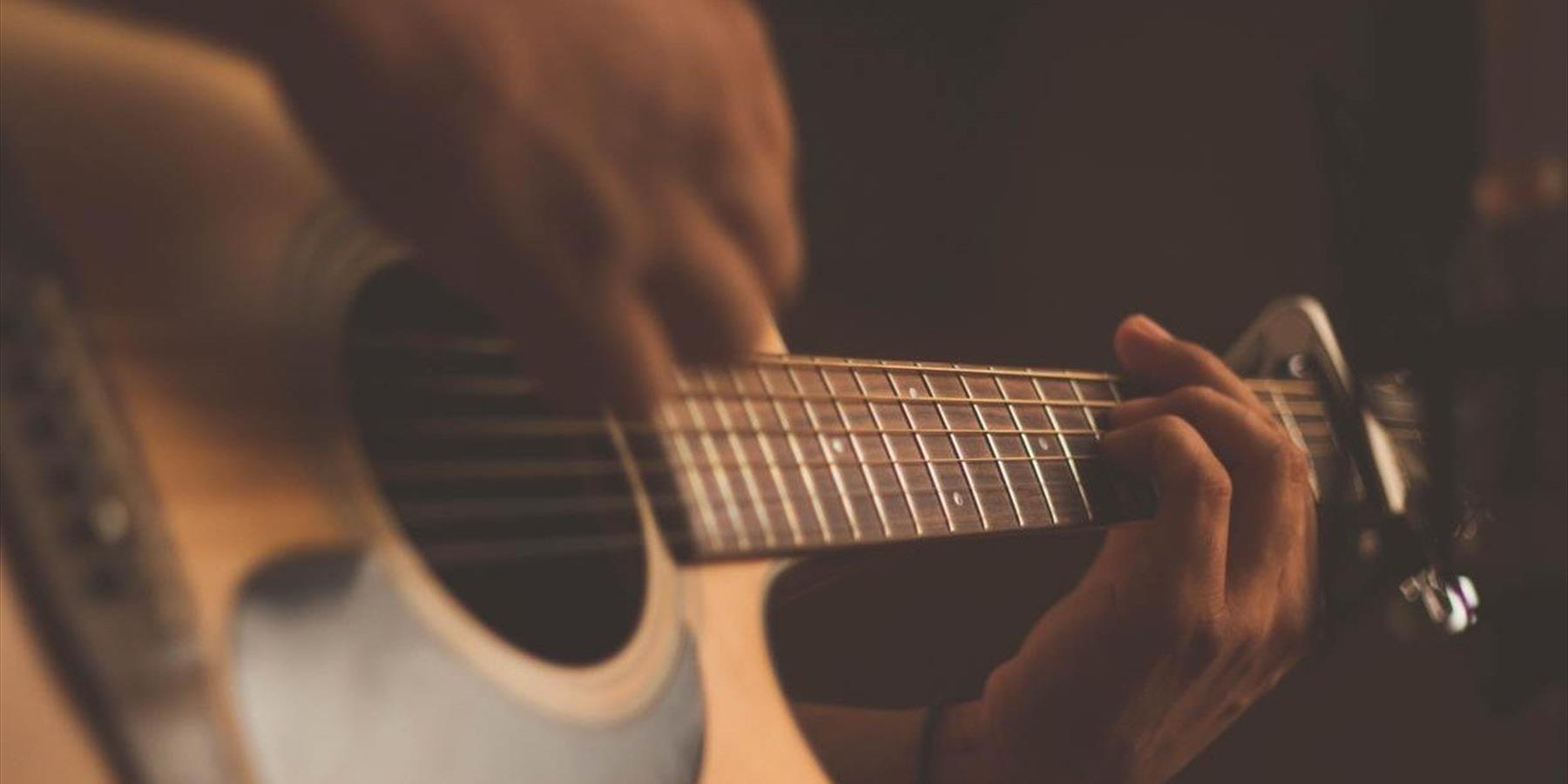 Person playing acoustic guitar with a capo