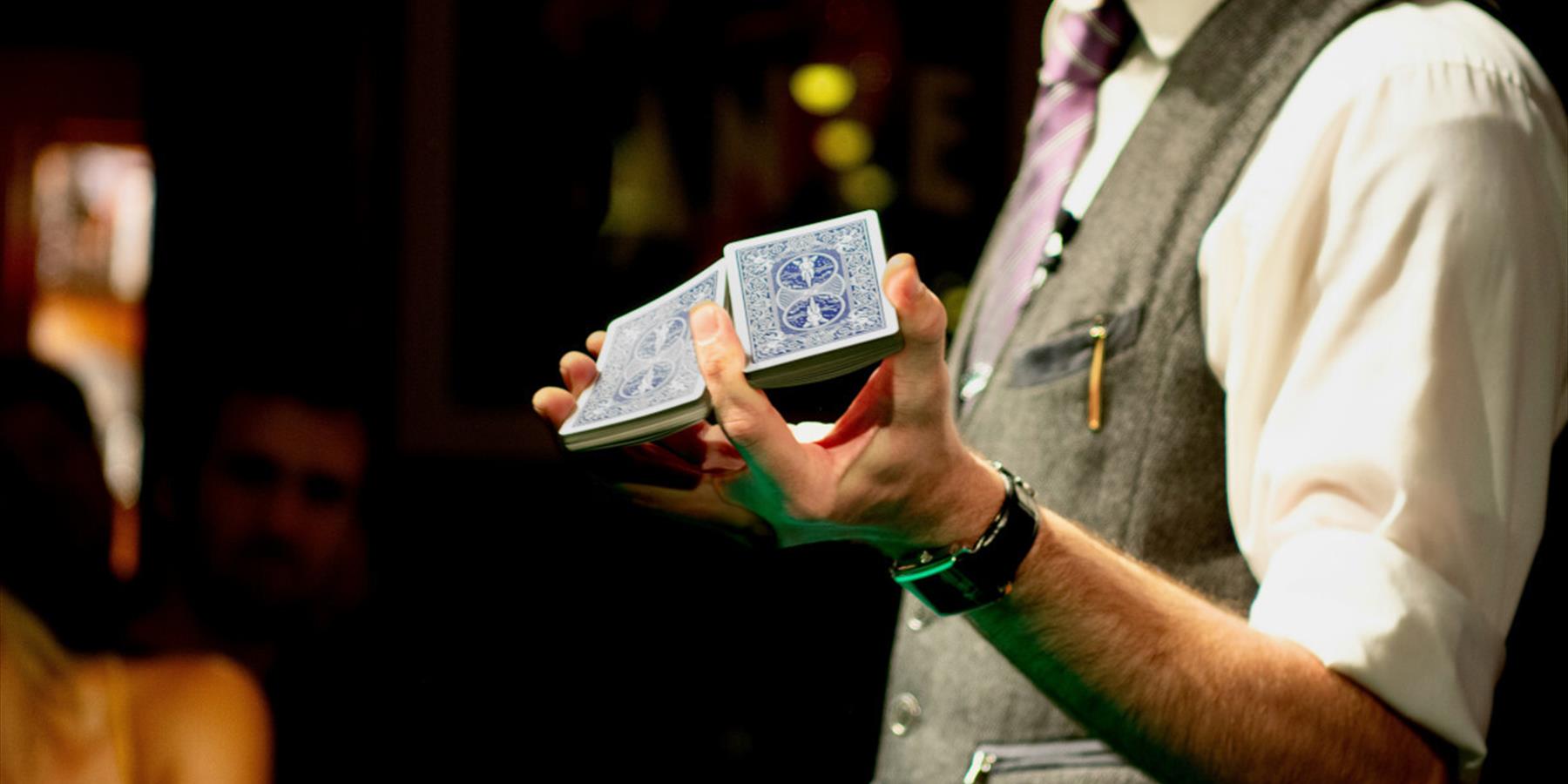 Person with grey waistcoat holding a deck of cards