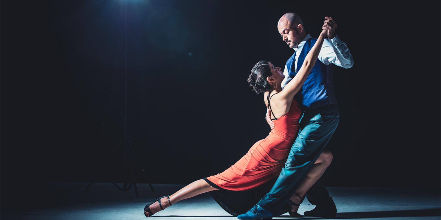 A woman in a red dress and her dance partner holding her