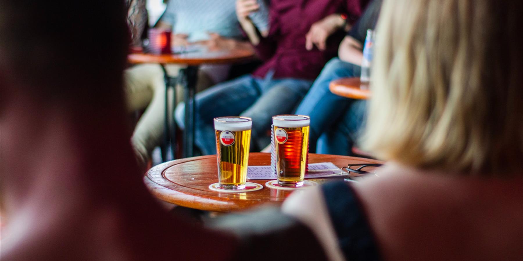 Two pints of beer on a table in a group of people