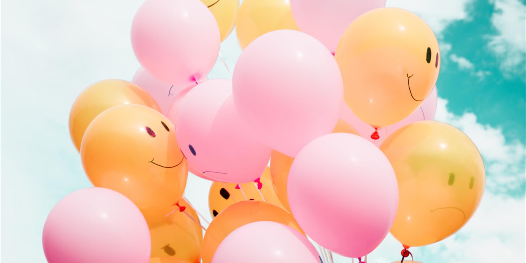 Yellow and pink balloons against a blue sky