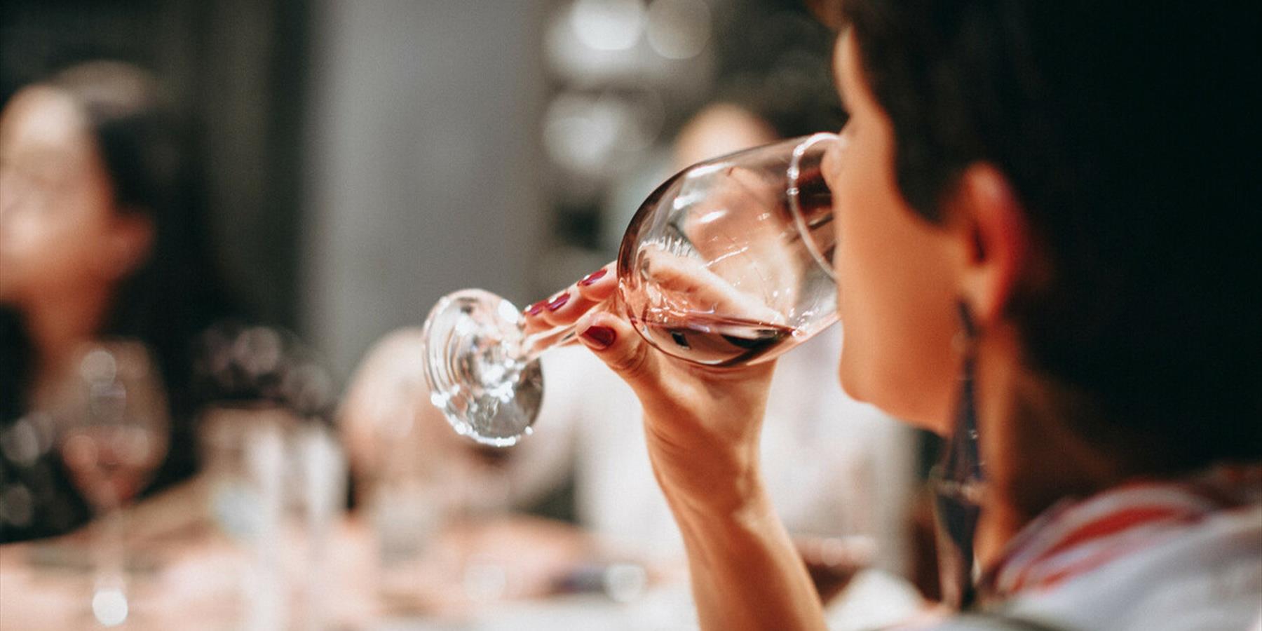 A person drinking from a clear wine glass