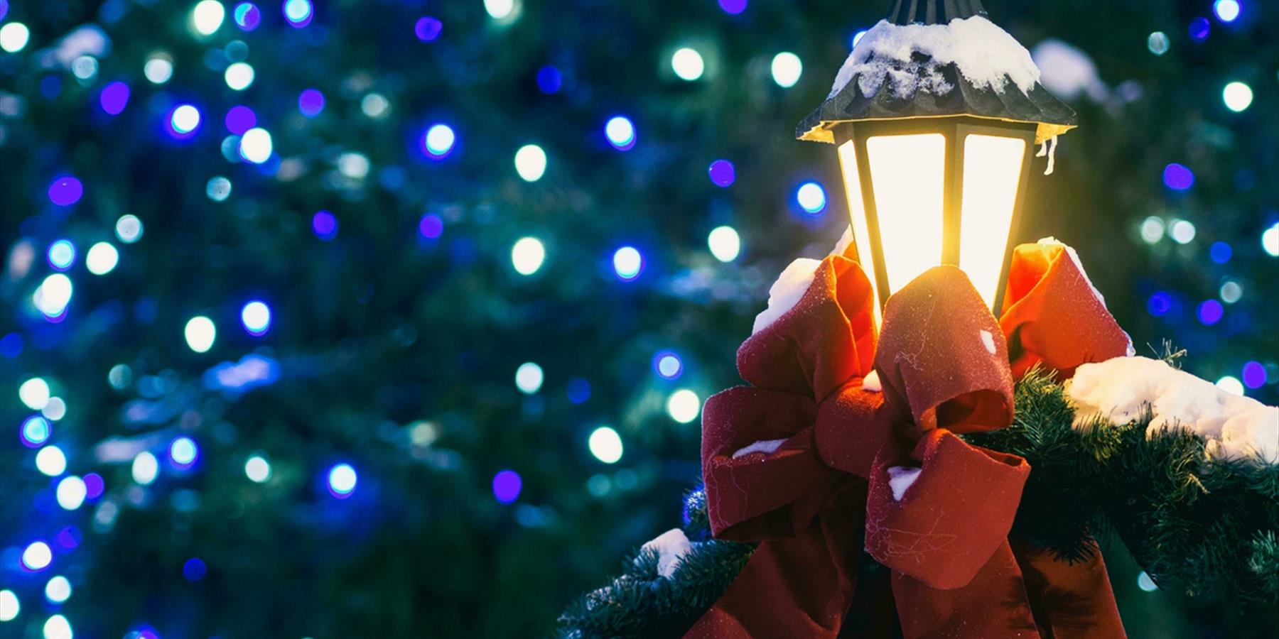 Outdoor lamp covered in snow and dressed with a red bow