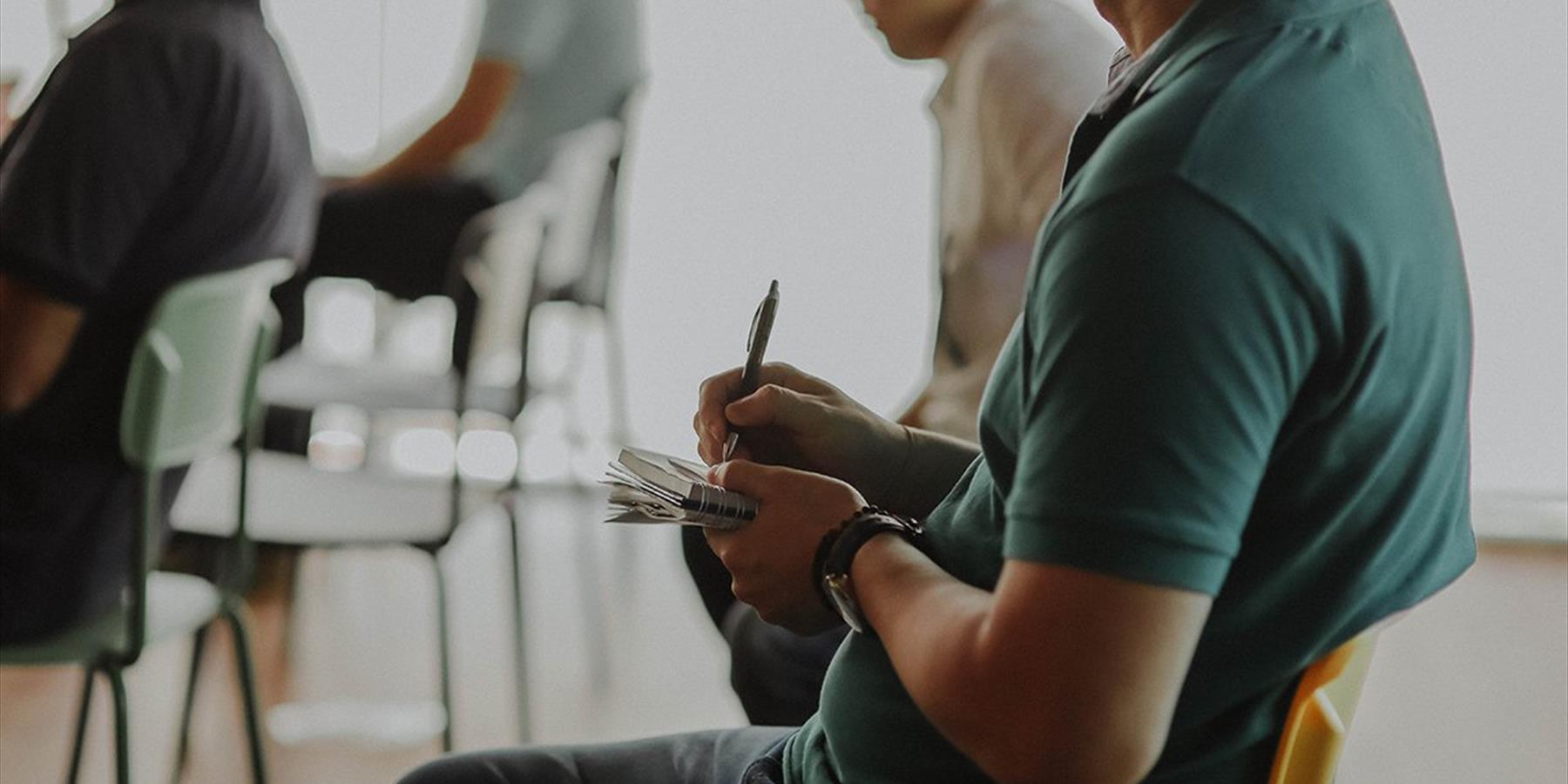 Person sitting in a chair taking notes on paper