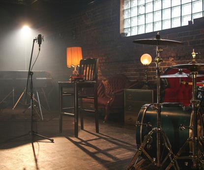 Microphone and drum kit in warmly lit room