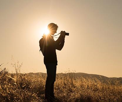 Person taking photographs in an empty field