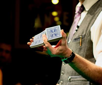 Person with grey waistcoat holding a deck of cards