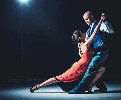 A woman in a red dress and her dance partner holding her