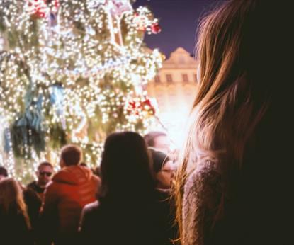 Person looking up at decorated outdoor Christmas tree