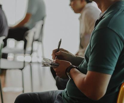 Person sitting in a chair taking notes on paper