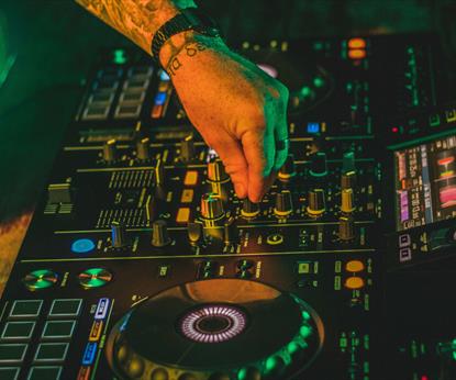 Electric mixing decks being operated by person with tattoos