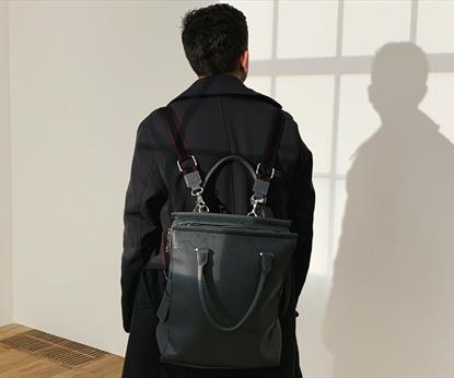 Person with black backpack and dark jacket looking at wall