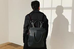 Person with black backpack and dark jacket looking at wall