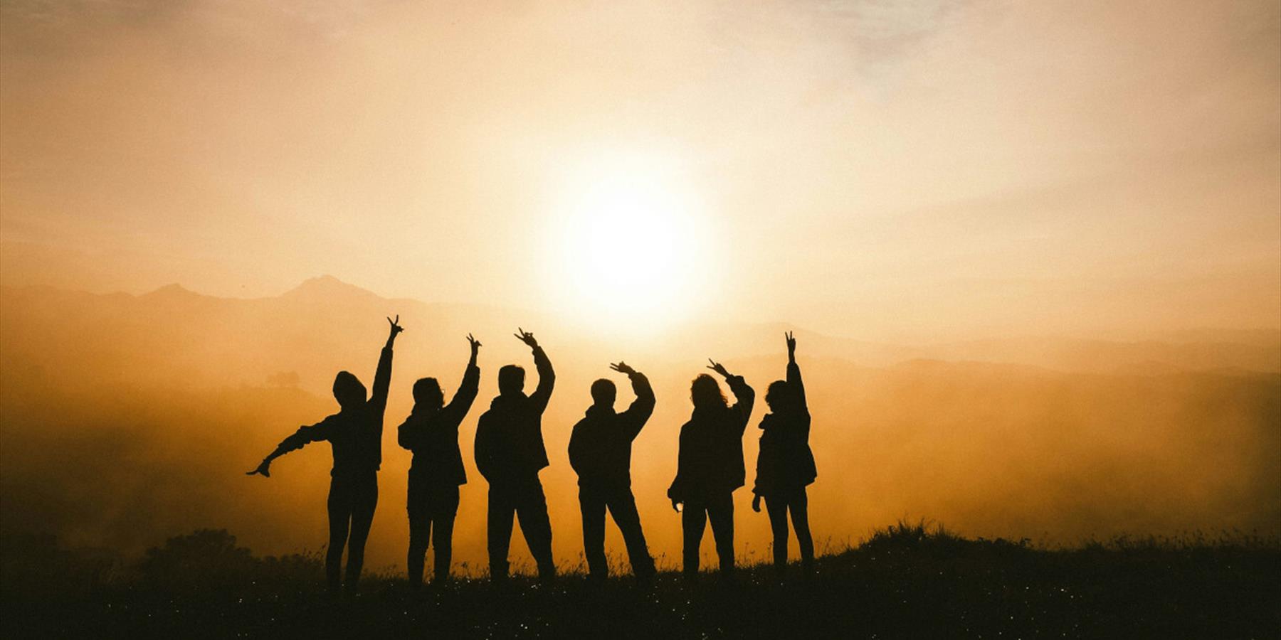 Silhouette of six people posing against a sunset