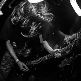 Black and white image of person with wild hair playing an electric guitar