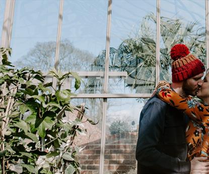 A couple kissing in a greenhouse