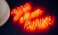A neon sign saying Pizza is the new punk