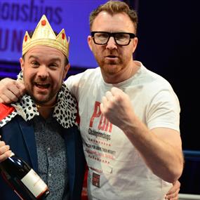 Two men one with a crown and trophy