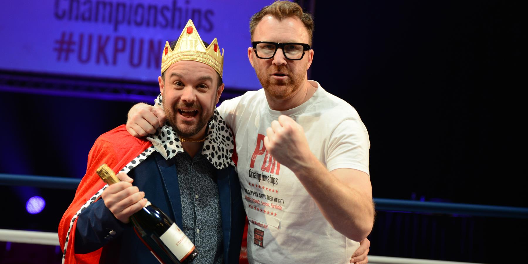Two men one with a crown and trophy