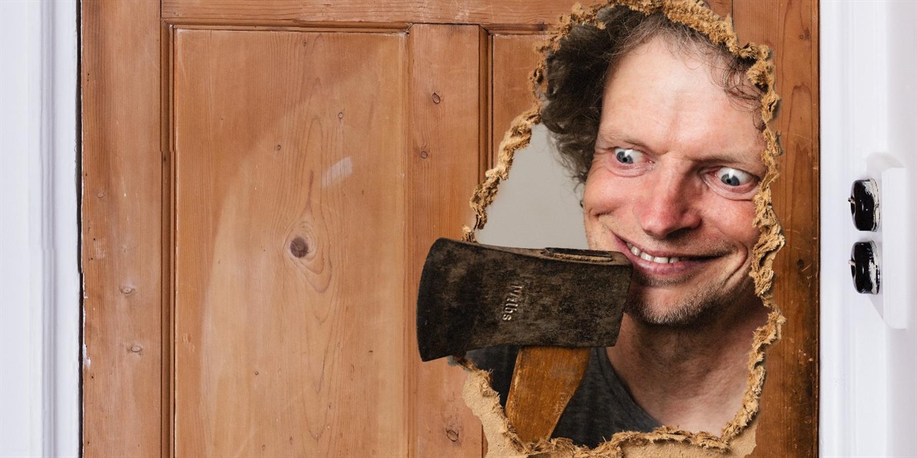 A man with an axe looking through a broken door