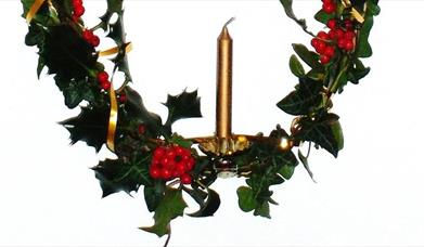 Advent candle surrounded by festive foliage.