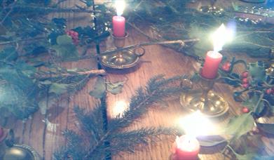 Festive table decorated with candles, fir branches and holly