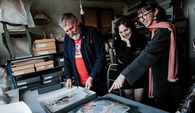 People discussing a range of paintings and documents
