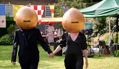 2 people in black with onion-shaped helmets on! in a garden setting