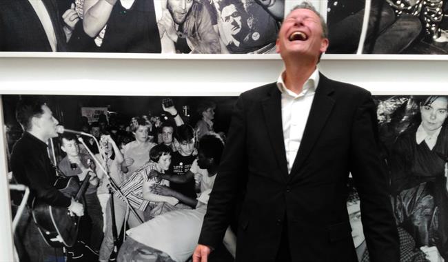 Gerry Colvin laughing in front of a photographic display