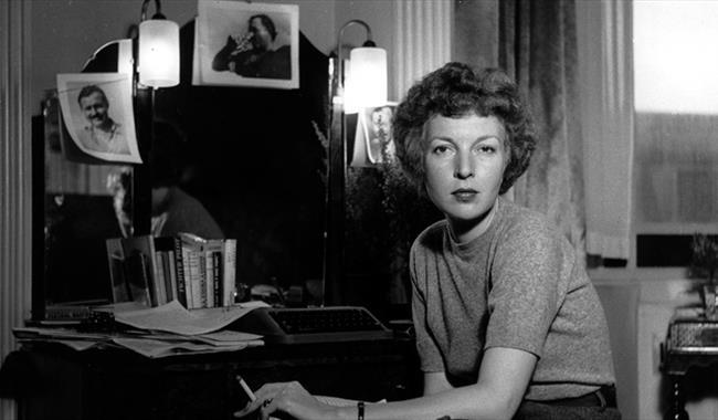 Lee Miller with photographs at her desk