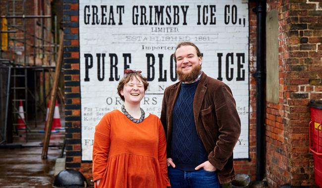 Mossy Christian & Megan Wisdom in front of a Great Grimsby Ice sign