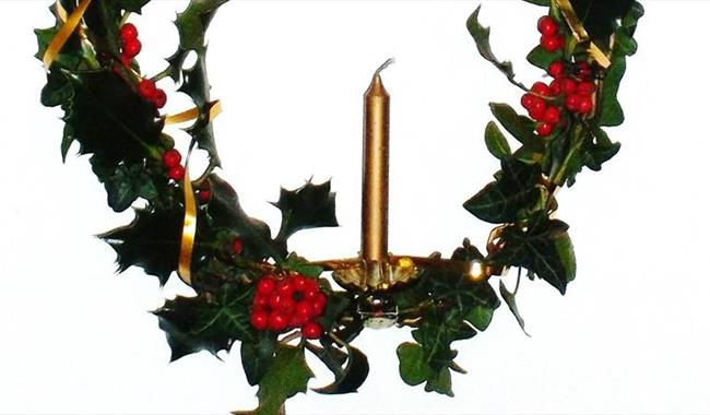 Advent candle decorated with festive foliage
