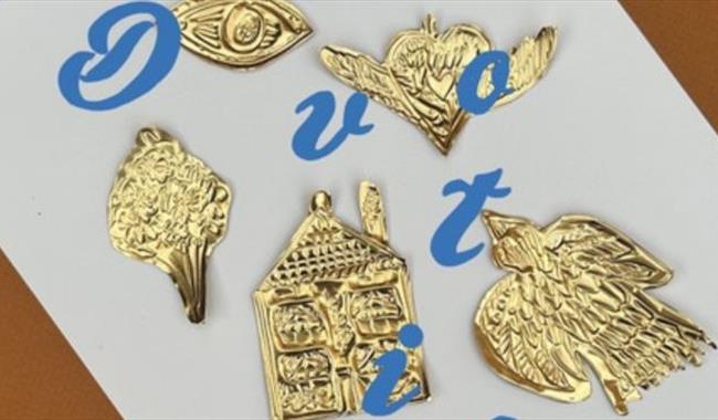 hand-embossed tin ornaments on a sheet of paper with letters spelling out devotion