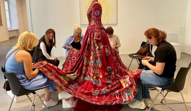 The Red Dress surrounded by embroiderers at work