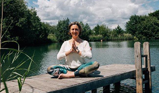 Woman doing yoga on a jetty by the river