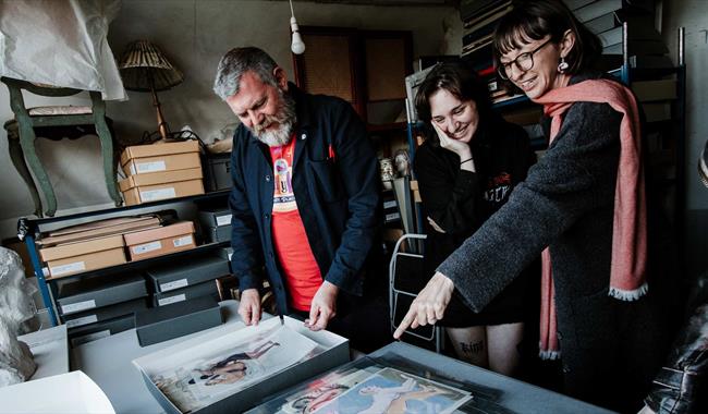 People discussing a range of paintings and documents