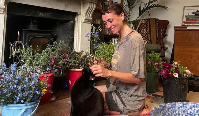 Woman with a cat surrounded by buckets of flowers