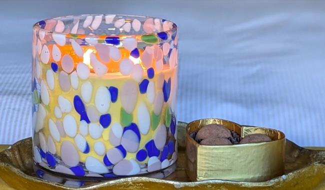 Handmade candle in coloured glass with box of chocolates
