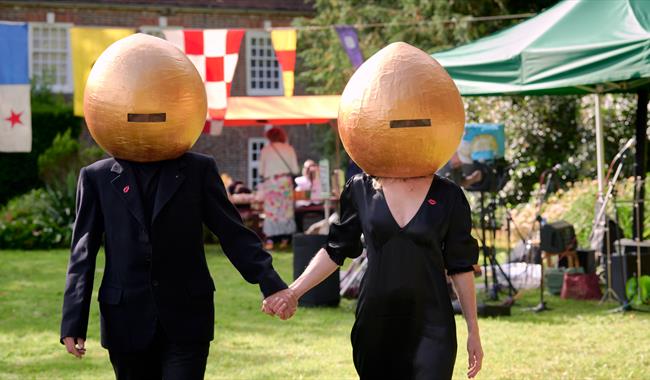 2 people in black with onion-shaped helmets on! in a garden setting