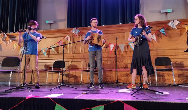 Folk musicians - Elye Cuthbertson, Danny Marshall and Mía Iles-Pérez on stage.
