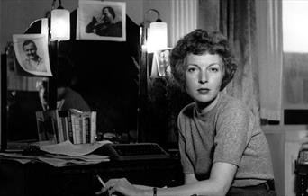 Lee Miller with photographs at her desk