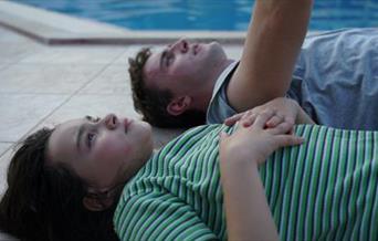 Father and daughter lie by the pool