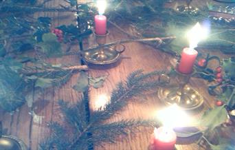 Festive table decorated with candles, fir branches and holly