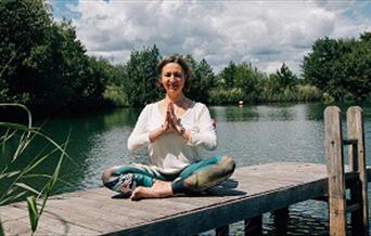 Woman doing yoga on a jetty by the river
