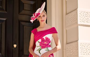 Woman dressed in elegant pink and white hat and dress