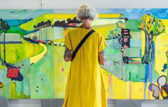 Woman in yellow dress looking at art