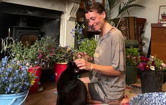 Woman with a cat surrounded by buckets of flowers