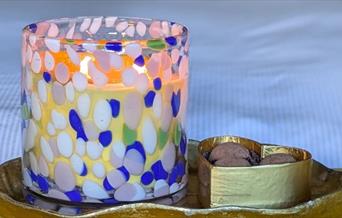 Handmade candle in coloured glass with box of chocolates
