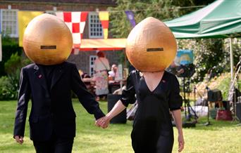 2 people in black with onion-shaped helmets on! in a garden setting
